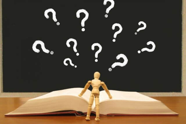 A book with question marks and a wooden figure